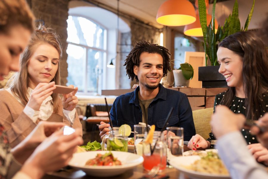 This is an image of a group of friends having lunch together around a table full of food.