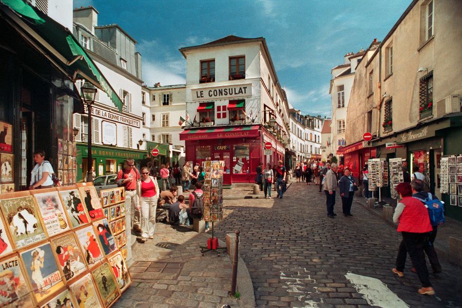 This is an image of the cobblestoned Montmartre streets with people milling around and souvenirs laid out on the street.
