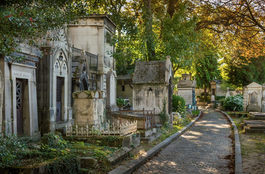 This is an image of a cemetery. There are gravestones and trees around but no people.