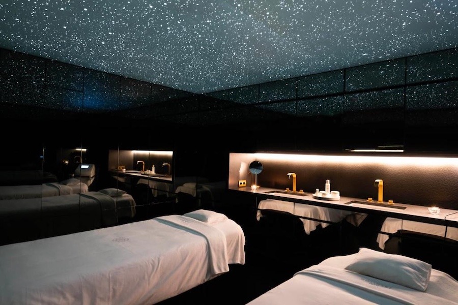 A dark massage room with a stars like ceiling, and two massage beds.