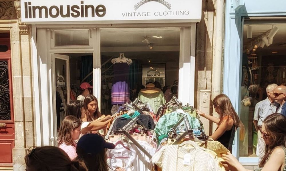 Best Shopping Areas in Paris: This is an image of a vintage store with people looking through racks on vintage clothes out the front.