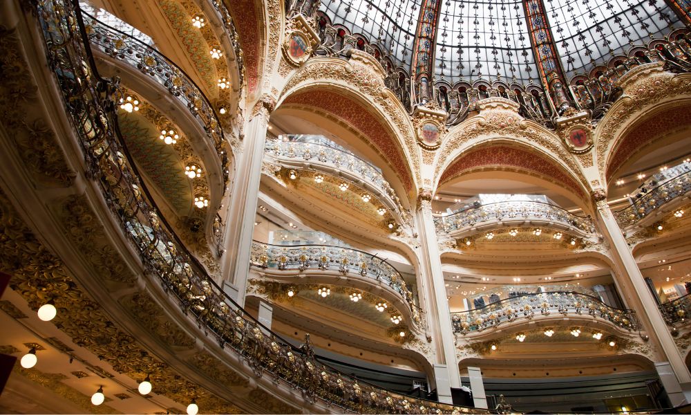 Best Shopping Areas in Paris: This is an image of a beautiful shopping mall with various levels and gold embellishments.