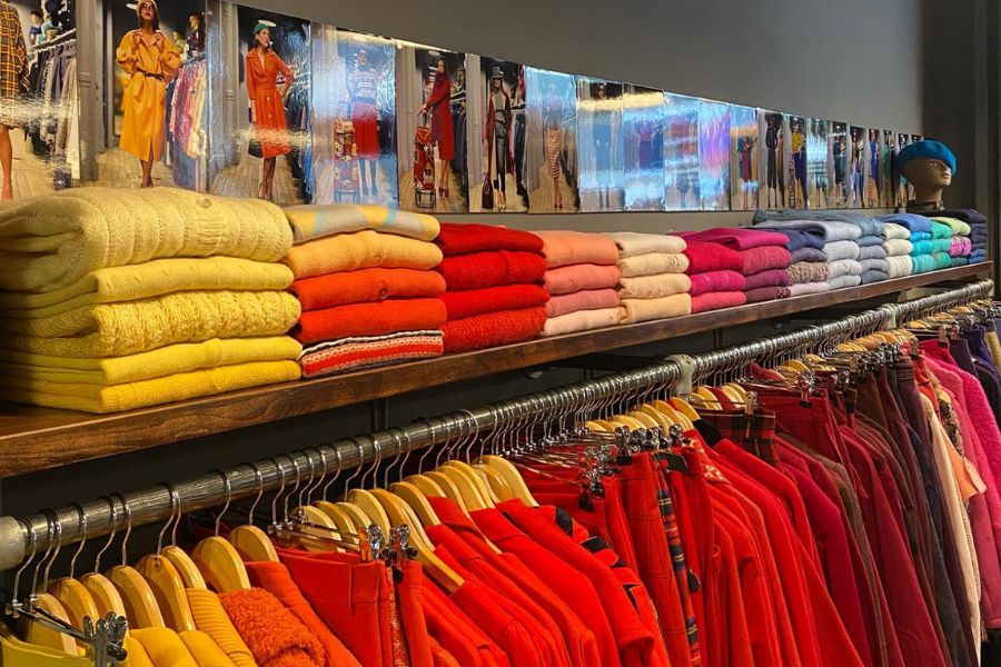 This is an image of a store where all the clothes are colour-coded and hung on different racks.