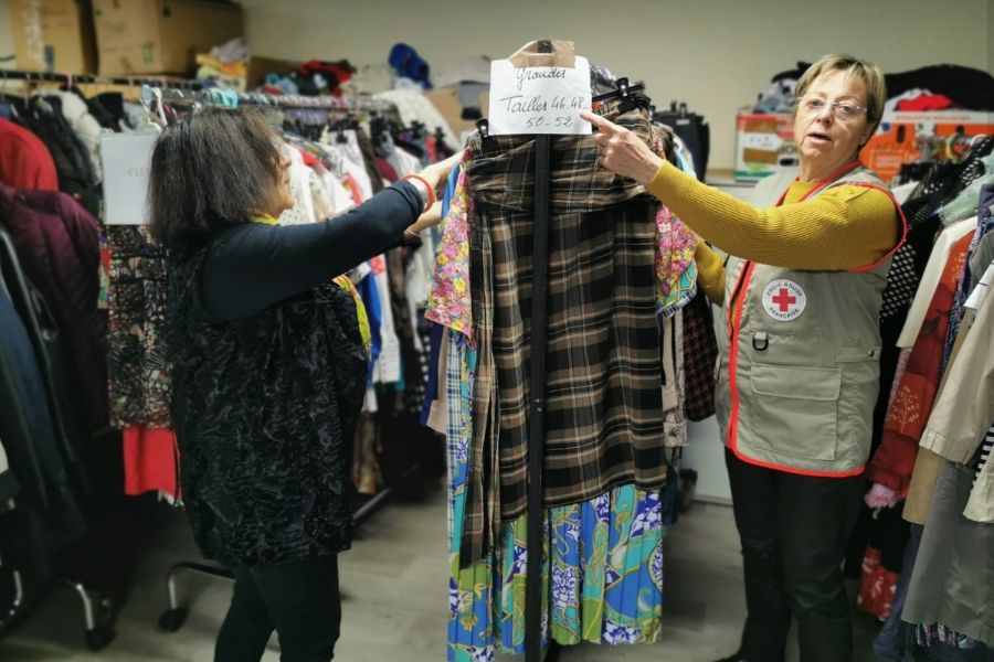 This is an image of two volunteers helping hang up clothes in a charity shop.