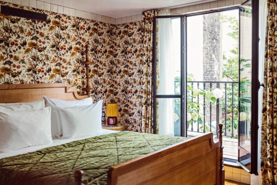 This is an image of a double bed with green cushions and a floral curtain hanging around the room.