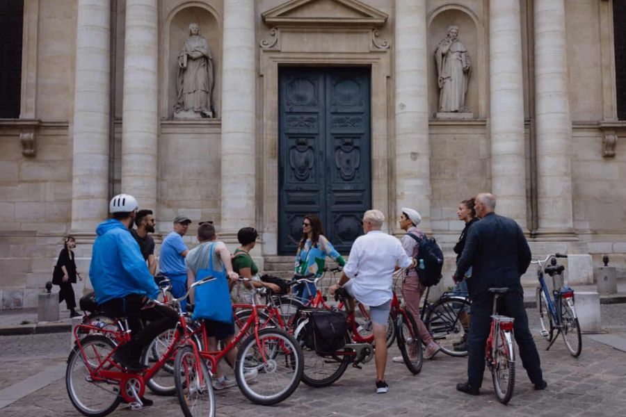 What to do in Paris During the Olympics: This is an image of a group of bikers on a tour outside a historic building.