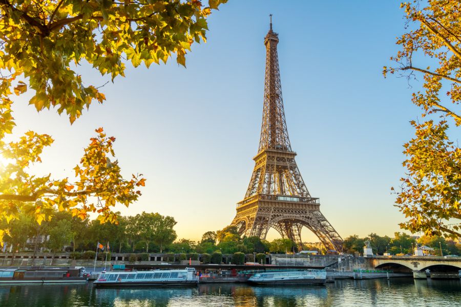 This is an image of the Eiffel Tower from across the Seine with boats lining the river.