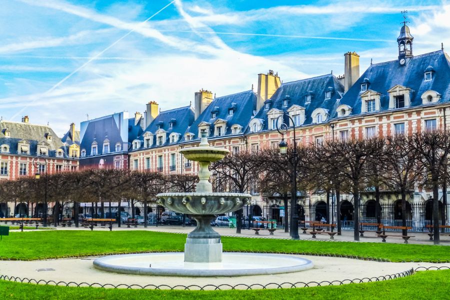 This is an image of Places des Vosges. The building surrounds the courtyard and there is a fountain in the middle.