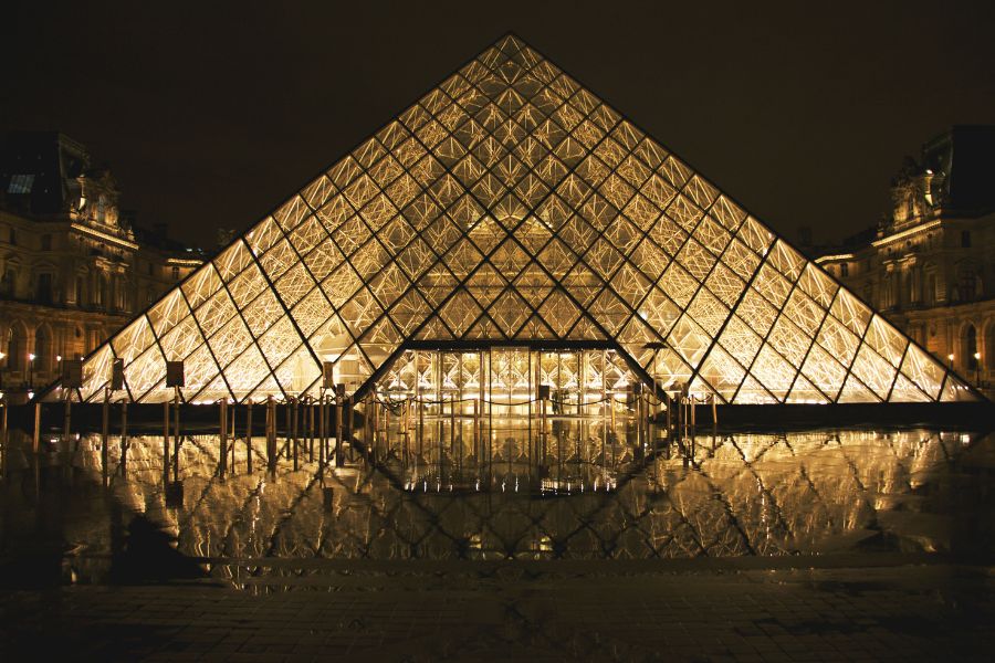 This is an image of the Louvre at night with light shining from within.