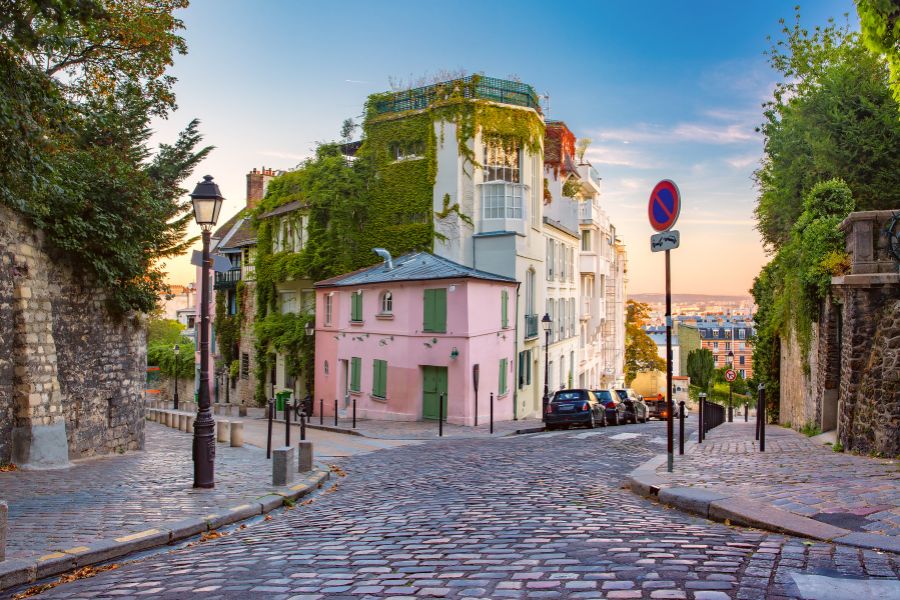 This is an image of an intersection in the middle of Montmartre with a pink building that you can see the city from.