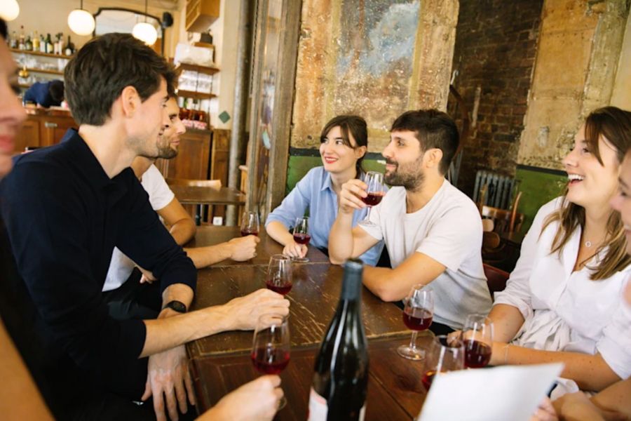 This is an image of a group of people laughing together and drinking wine.