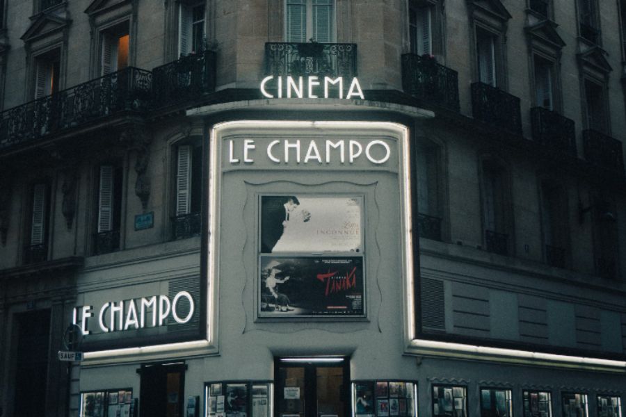 This is the exterior of an old cinema called Le Champo with big lights and movie premiere pictures at the front.