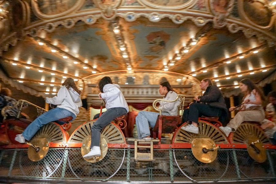 This is an image of five kids on a Merry Go 'Round that's all lit up.