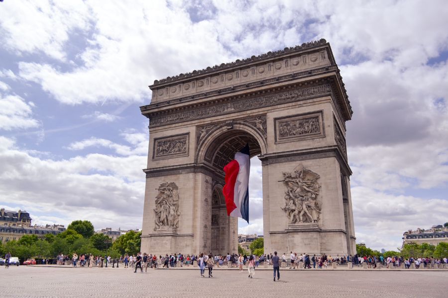 The Arc de Triomphe with a large French flag hanging beneath the arch, crowds gathered below