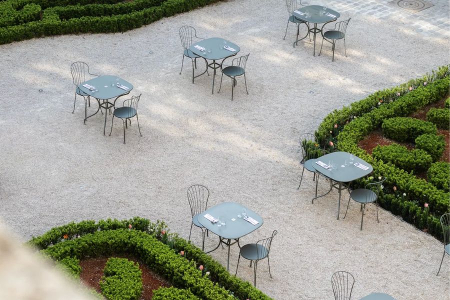 Aerial view of empty café tables set among manicured hedges in a Parisian garden