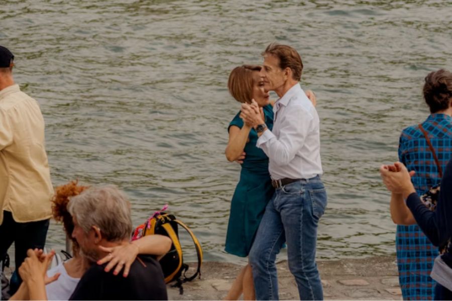 An older couple dancing together on the banks of the Seine in Paris