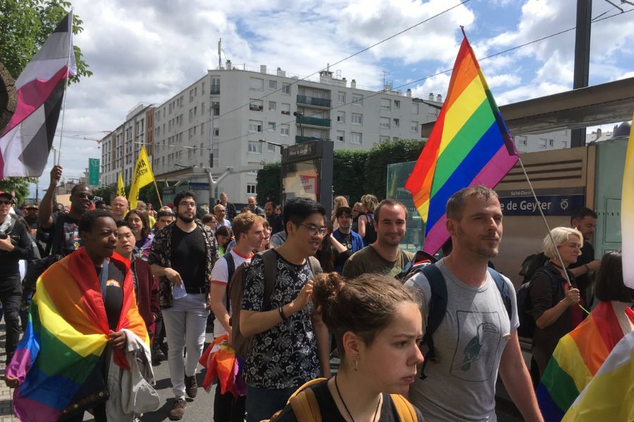 Crowds marching with rainbow and pride flags at a Pride march in Paris