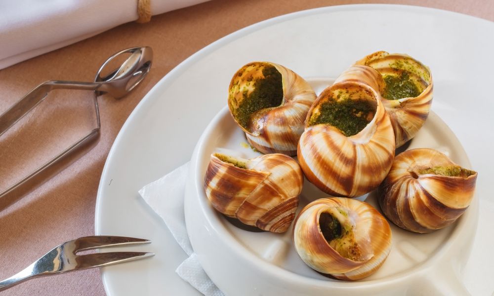 This is an image of a plate full of snails with a herby sauce.