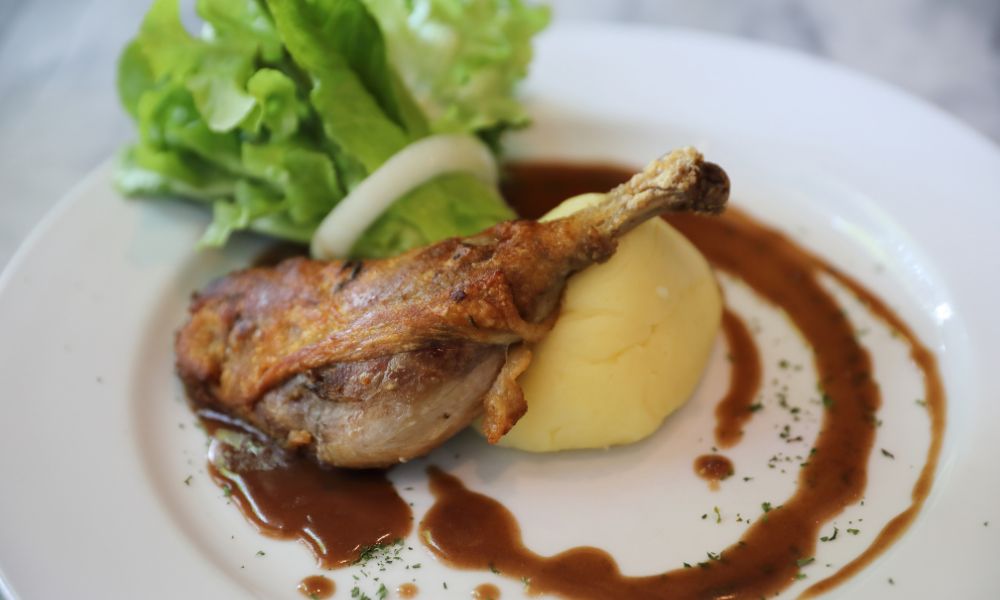 This is an image of a duck leg on a bed of potato.
