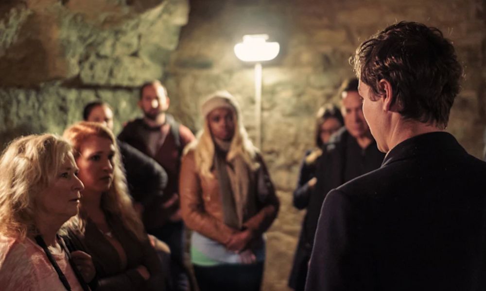 This is an image of a tour group being led by a tour guide in the Catacombs.