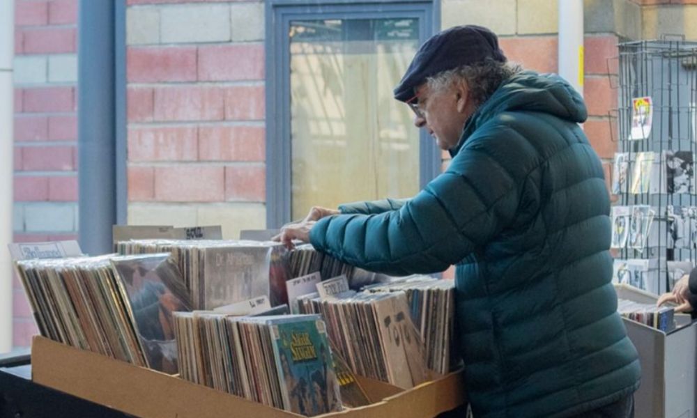 This is an image of a man going through old records at a vintage market.