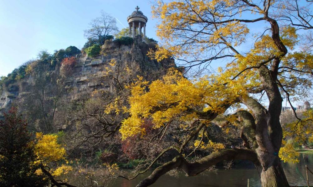 This is an image of a beautiful park with a pagola on top of a hill.