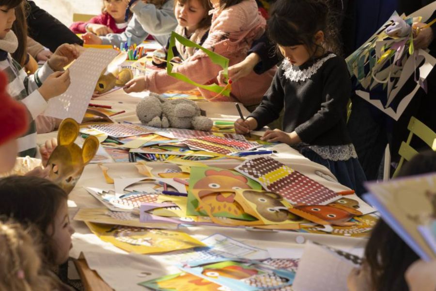 This is an image of kids at a craft table colouring Easter prints and cutting out paper.