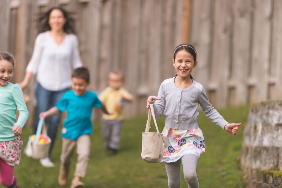 This is an image of young kids collecting Easter eggs with their parents in tow behind.