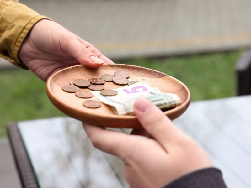 This is an image of someone handing someone else a plate of euros as a tip.
