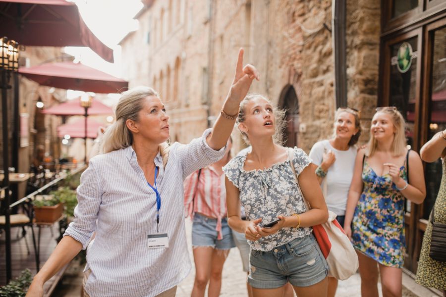 This is an image of a tour guide pointing up to something in the distance. The tour group is following her finger.