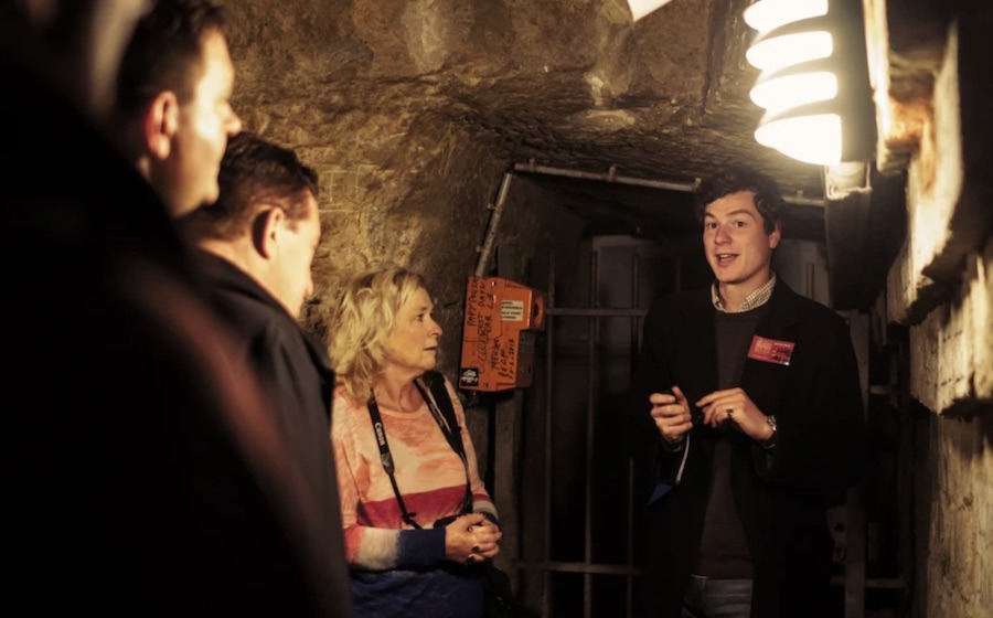 This is an image of a tour guide taking a group down into the catacombs of Paris.