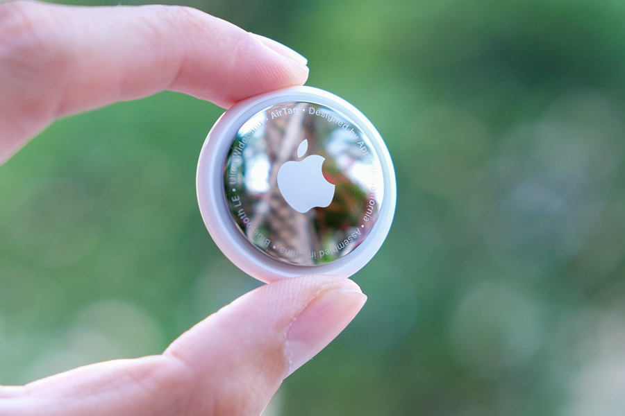 Apple AirTag held between two fingers, a useful anti-theft travel device for tracking luggage and valuables during a Paris trip.
