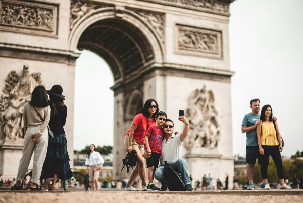 Tourists taking photos at the Arc de Triomphe, with anti-theft travel devices helping keep valuables secure while exploring Paris.