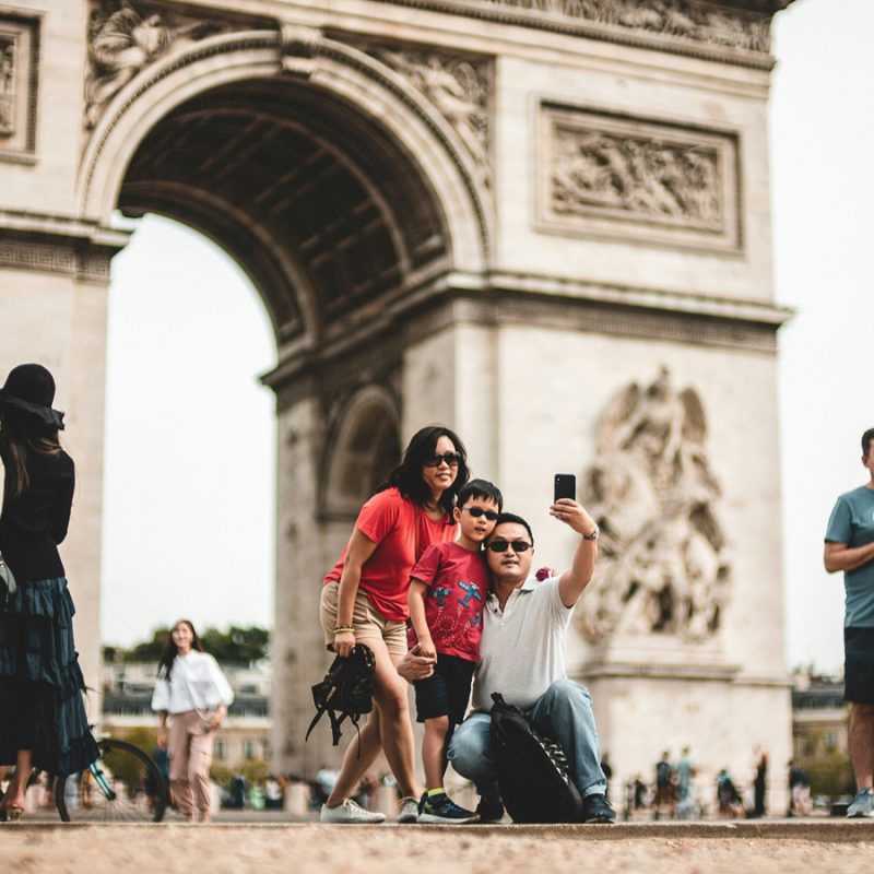 Tourists taking photos at the Arc de Triomphe, with anti-theft travel devices helping keep valuables secure while exploring Paris.