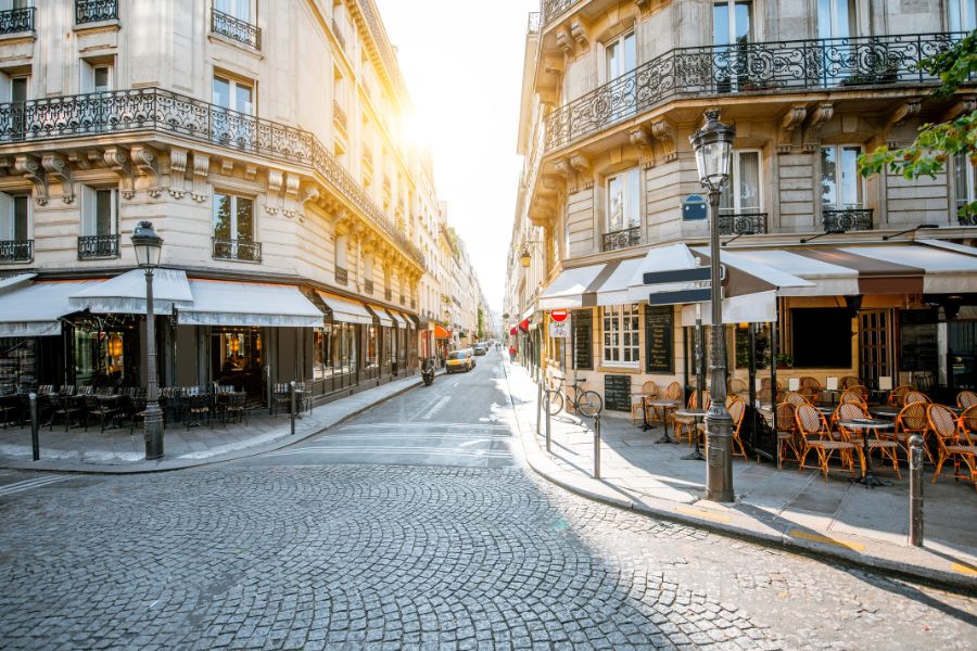 This is a picture of a Parisian street with cafés lining the corner of the streets. There are no people around.