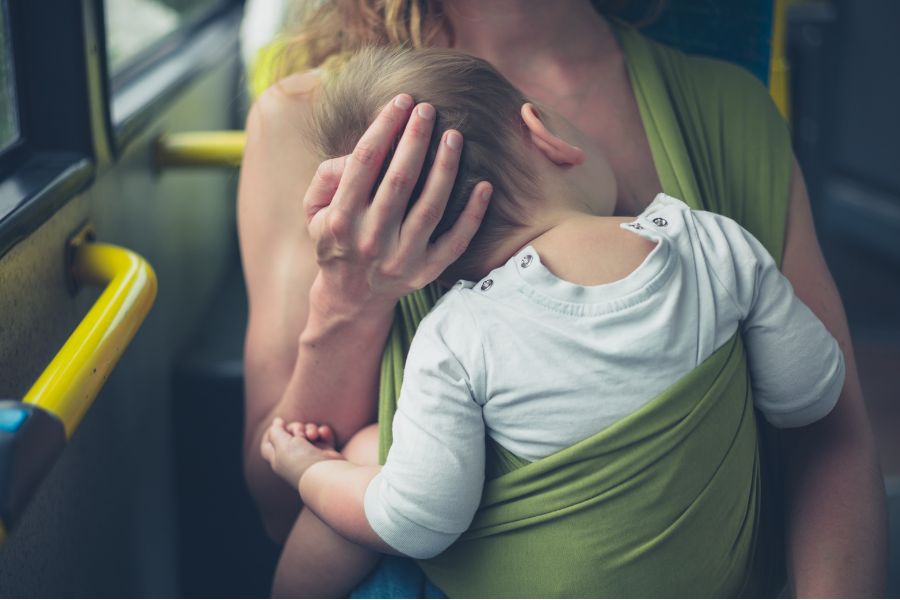 This is a picture of a baby in a sling laying on its mother's chest.