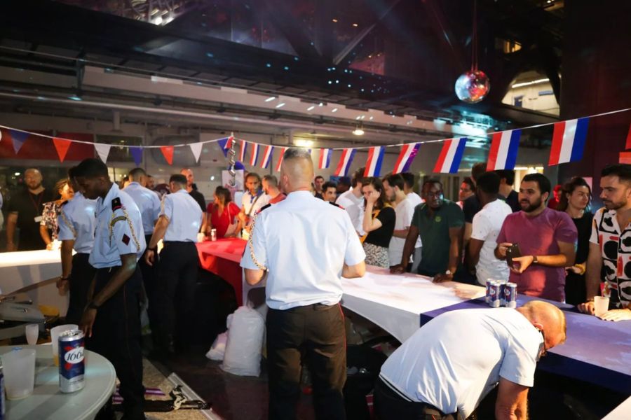 This is a picture of a ball held at a fire station, where the fire fighters and staff are serving drinks and enjoying music.
