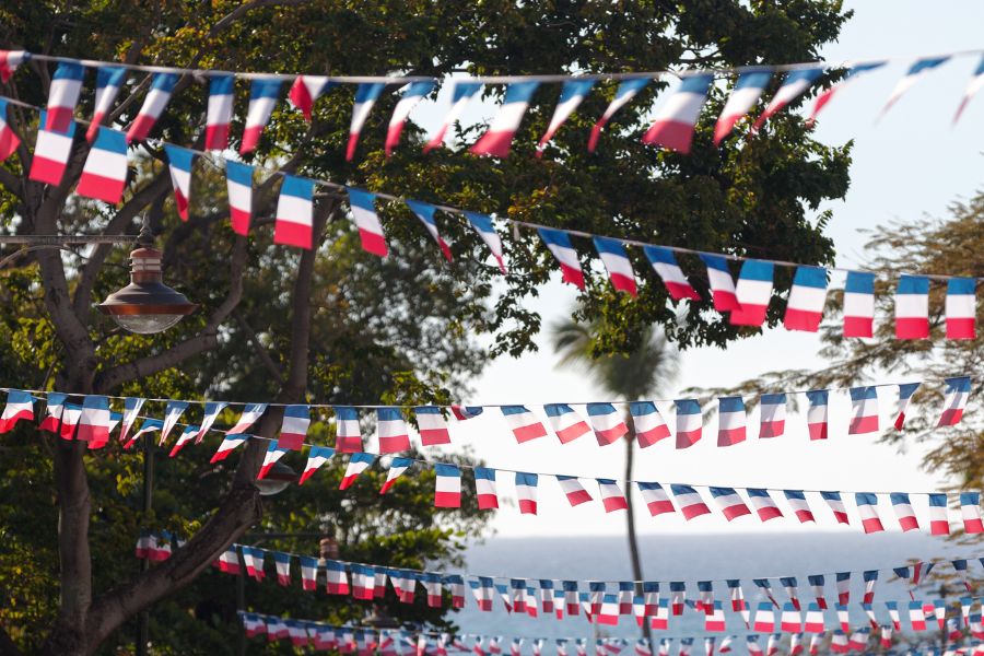 This is a picture of a party street full of string that adorns French flags for Bastille Day.