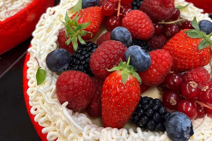 Red velvet cakes topped with whipped cream and piled high with fresh berries, including strawberries, blueberries, raspberries, blackberries, and red currants, at Boulangerie La Parisienne.