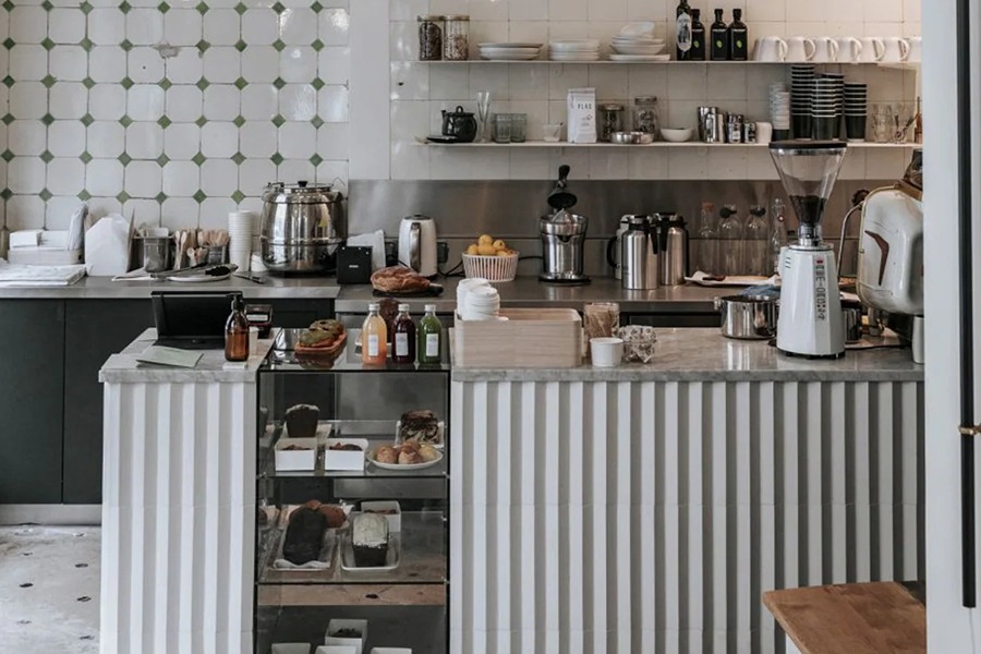 Interior counter of the No Glu gluten-free bakery and café in Paris, with a fluted tile bar, espresso equipment, fresh juices, and pastries displayed in a glass case.