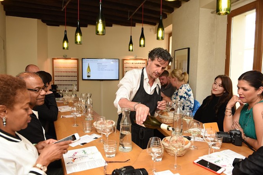This is an image of a wine tasting event with people sat at a table tasting an array of wines.