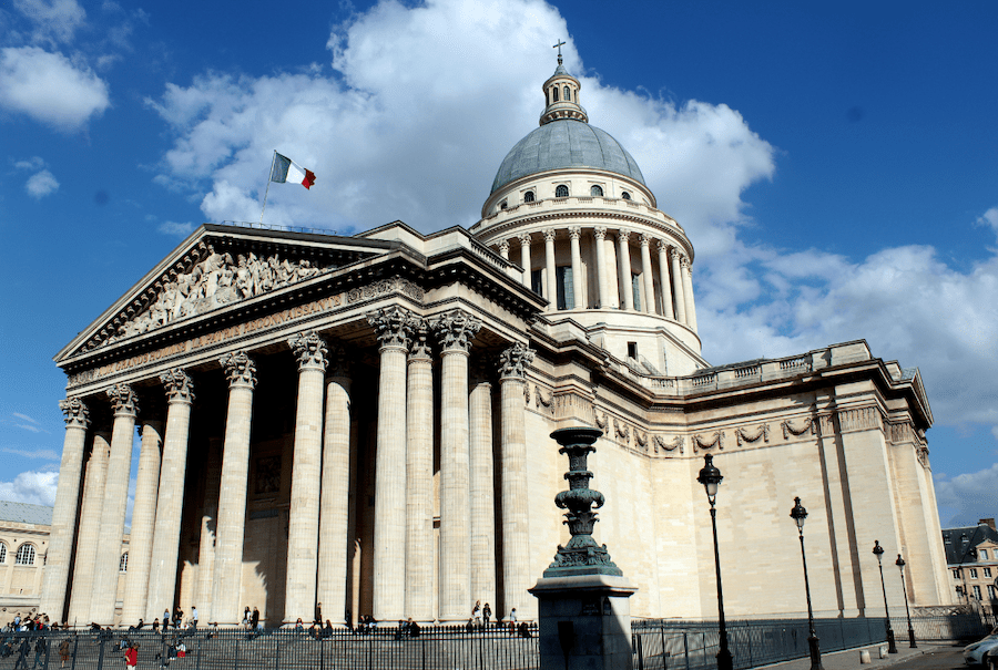 This is an image of the facade of a grand building with blue skies in the backdrop.
