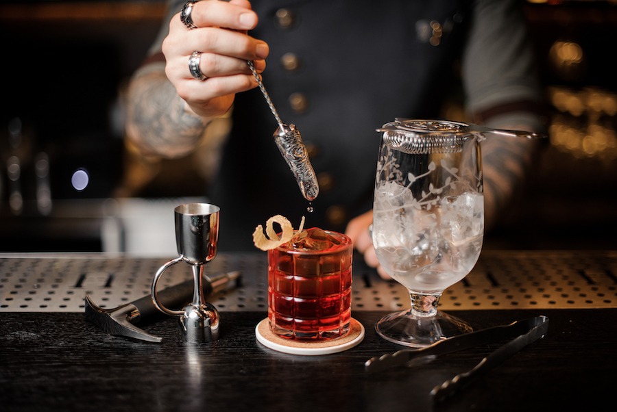 This is an image of a man mixing a cocktail in a cool bar.