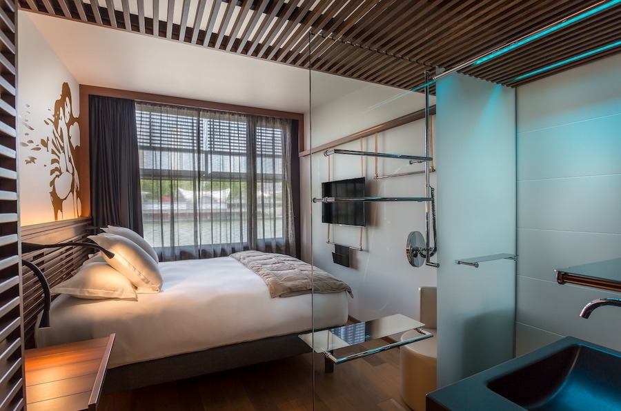 This is an image of a hotel bedroom with a walk in shower and a big double bed. A great Budget Friendly Hotels in Paris.