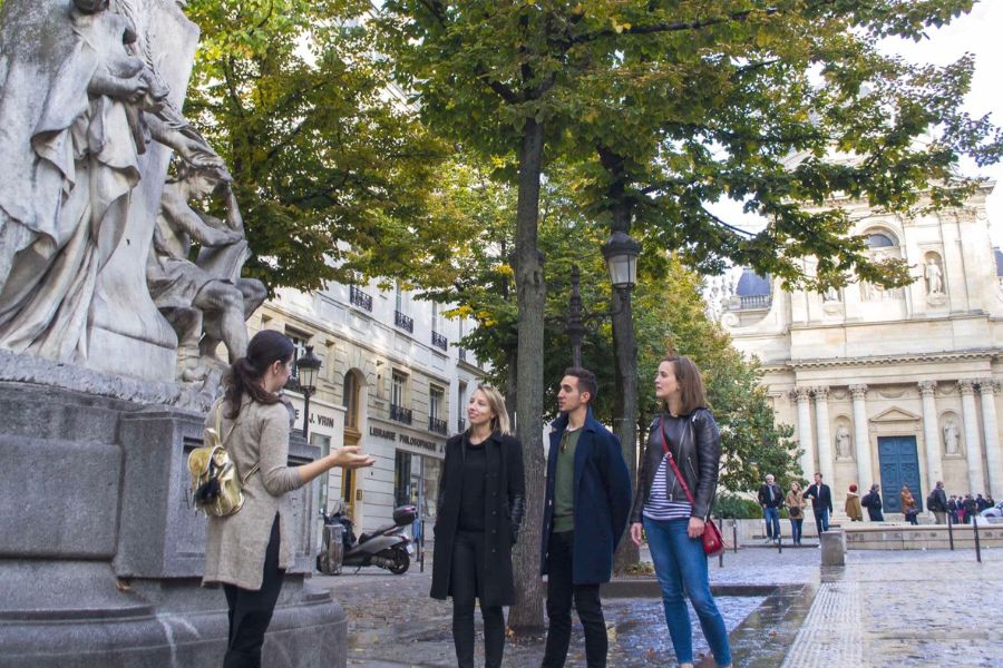 This is a picture of people on a tour with a tour guide in front of an important statue.