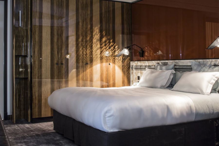 This is an image of a nice hotel room. The double bed has a white duvet, and the bedside lamp is on to give the room a nice ambience.