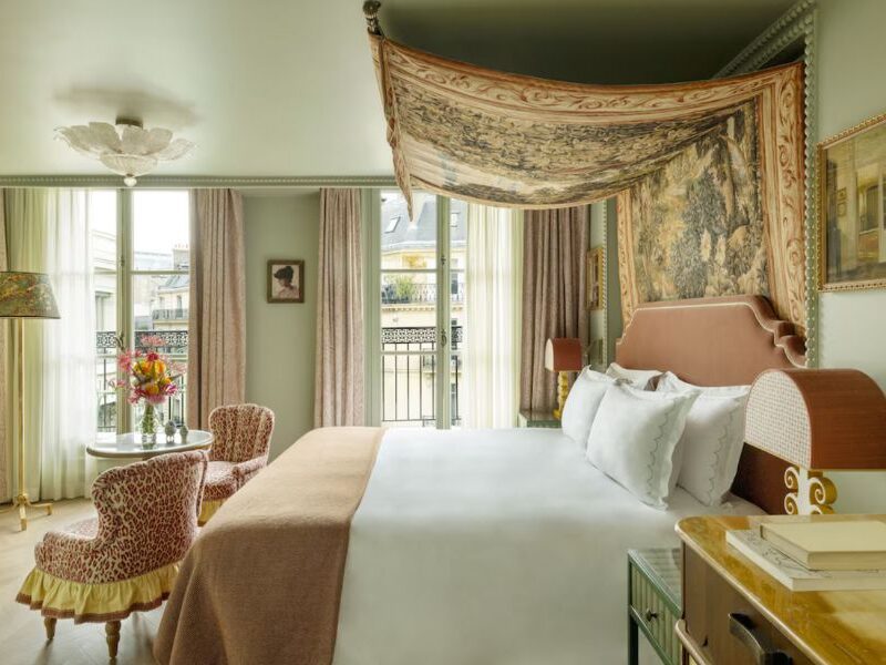Cool Hotels In The Marais Paris: This is a very art-deco hotel room with lots of natural light. There is a large colourful canopy draped over the bed.
