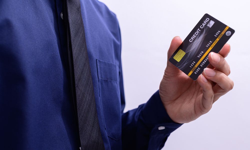 This is an image of a man holding a credit card wearing a suit.