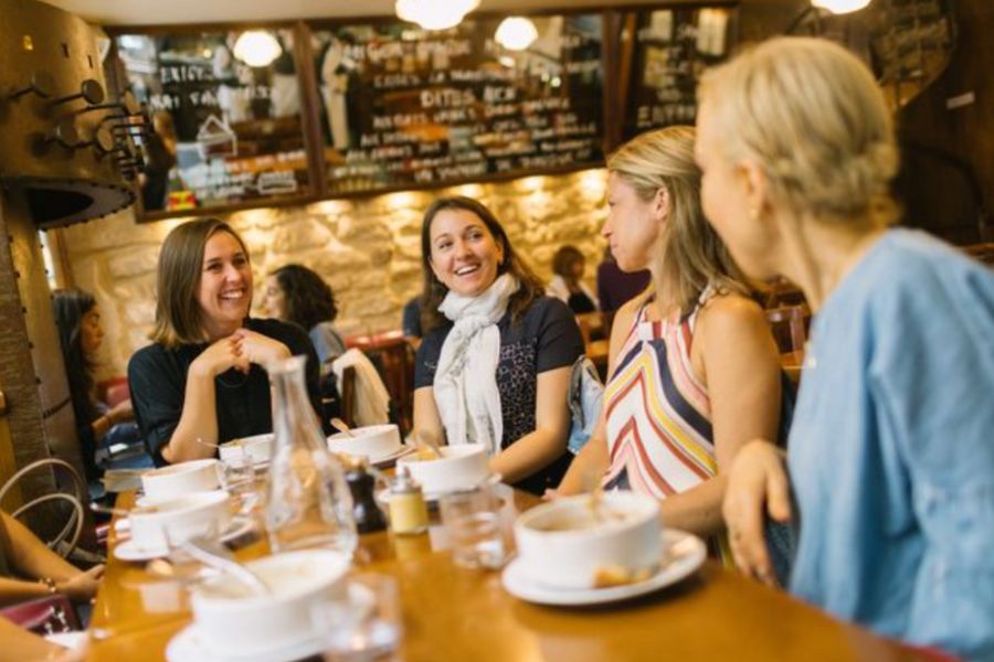 This is an image of a group of people on a food tour sitting at a table laughing and eating.