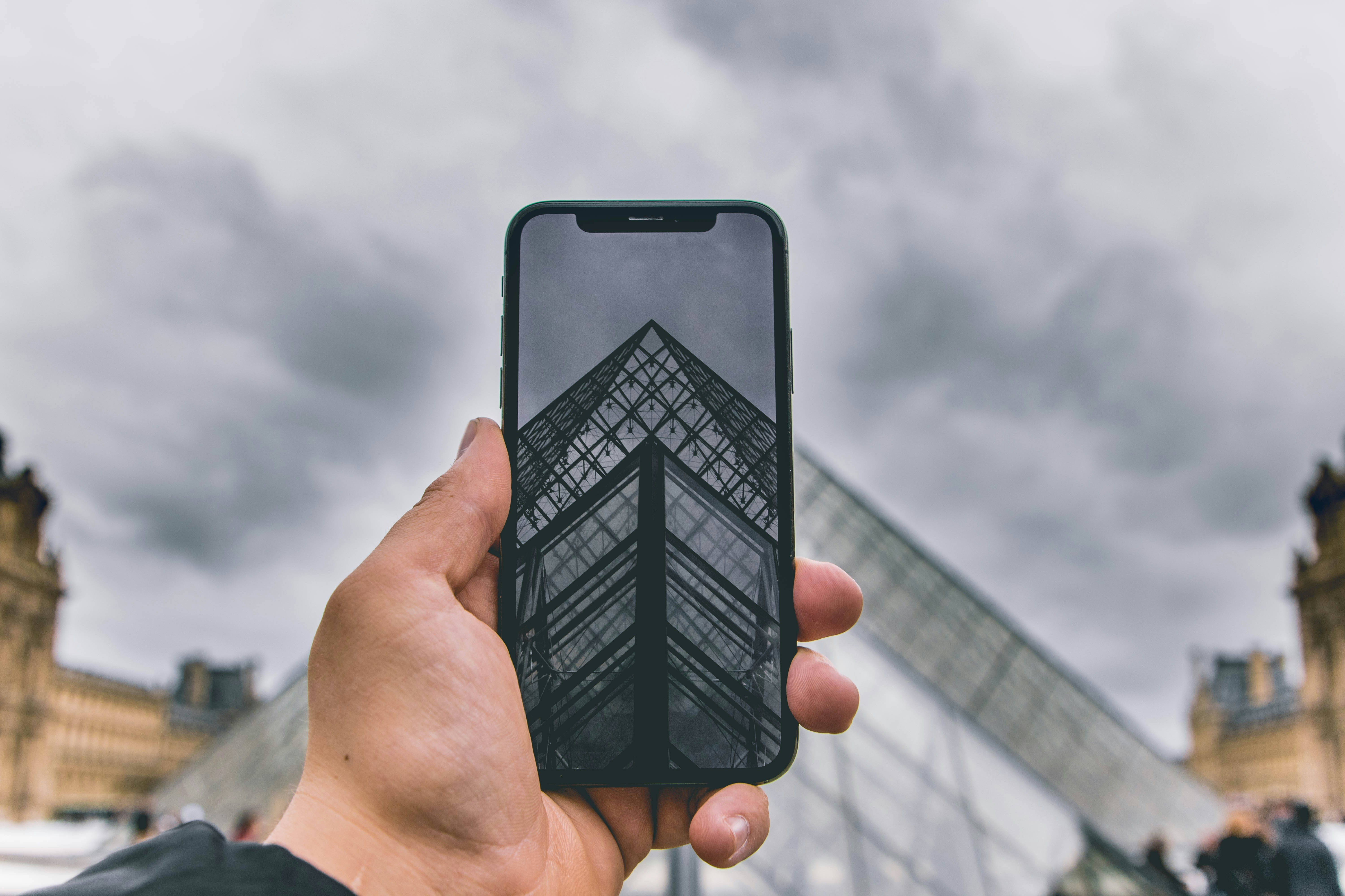 A person holds their phone whilst outside the Louvre.